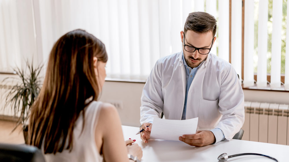 Junger Arzt mit Patientin im Gespräch